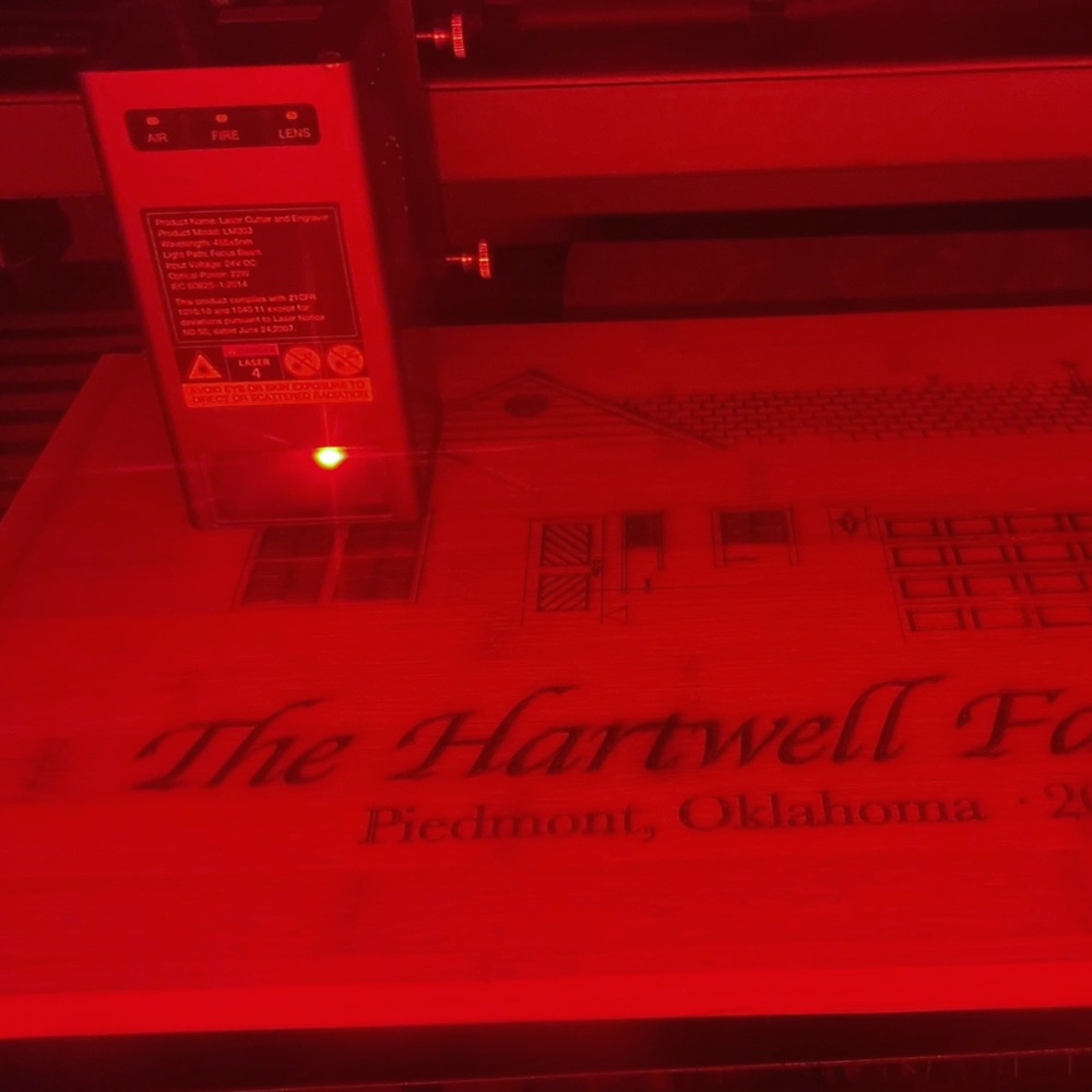 The cutting board being engraved inside a red-lit laser enclosure